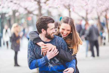 Young hipster couple embracing and smiling in Stockholm with cherry blossoms at Kungstradgarden, the swedish for Kings Garden. Love and friendship concepts with a hipster theme.の写真素材