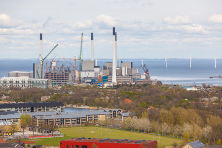 Power plant in Copenhagen next to the sea, the strait of Oresund, with high cimneys and wind turbines. Panoramic aerial view.のeditorial素材