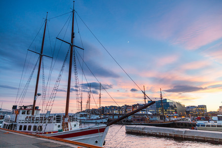 Oslo harbor with boats and yachts at twilight. There are both private and touristic boats, and on some modern buildings.の写真素材