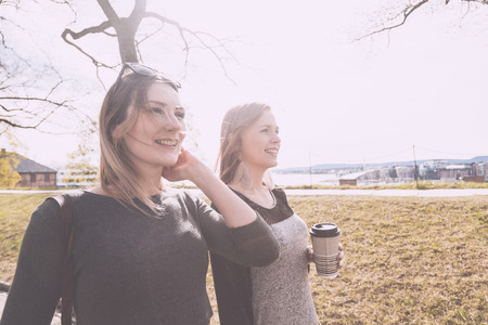 Two beautiful nordic girls walking at park in Oslo, talking and laughing. Lifestyle and friendship concepts.の写真素材