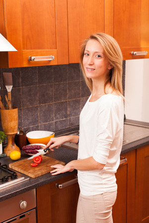 Young Woman Cutting Tomato in the Kitchenの写真素材
