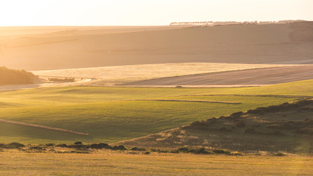 Panoramic view of English countryside at sunset. There are some cultivated fields with different colors. Photo taken next to Beachy Head, in Sussex region. Nature is the main concept.の写真素材