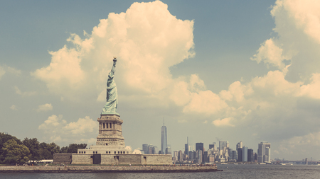 Statue of Liberty with New York skyline on background. Vintage filter added. Panoramic composition with text space on right side. Travel concept with a postcard style.の写真素材