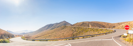Panoramic view of a mountain road in Fuerteventura island, Spain, on a sunny day. There are bare mountains all around and nobody on the road. Travel and nature concepts.の写真素材
