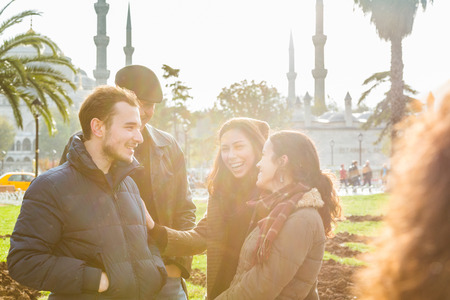 Group of Turkish friends in Istanbul. They are two men and two women, talking and laughing, with a mosque on background.の写真素材