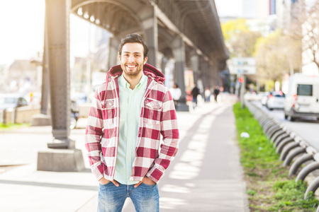 Portrait of an handsome young man in Hamburg. He is middle eastern, on his early twenties. He is looking at camera and smiling. Real people portrait with candid expressionの写真素材