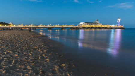 Pier in Bournemouth at night. Long exposure shot, with blurred water and people. The beach is almost emptyの写真素材