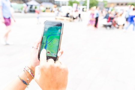 LONDON, UK - July 30, 2016: Woman playing with the current fashion app Pokemon go on an Apple iPhone...