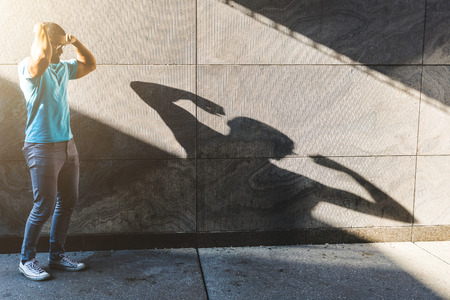 Man playing with his shadow on the wall. Black young man showing his muscles