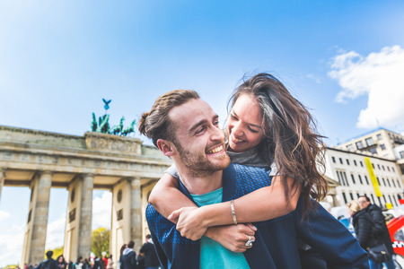 Happy couple having fun in Berlin. Mixed race couple, a caucasian man giving a piggyback ride to his girlfriend, an asian woman. Happiness, lifestyle and tourism conceptsの写真素材