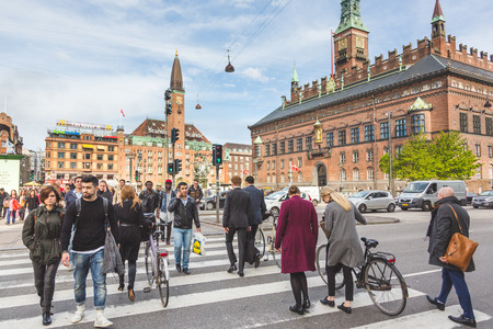 COPENHAGEN, DENMARK - APRIL 27, 2015: People crossing on zebra in the city. Commuters and tourists walking and carrying bicycles. City hall on backgroundのeditorial素材