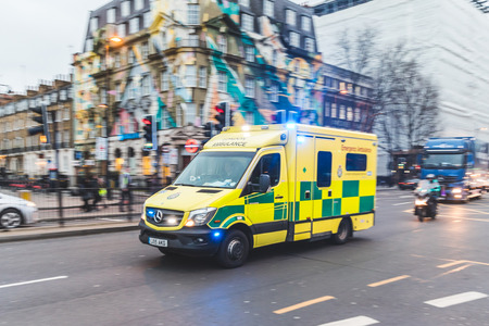 LONDON, UK - MARCH 1, 2017: Emergency ambulance rushing on the street with emergency lights flashing in London city centreのeditorial素材