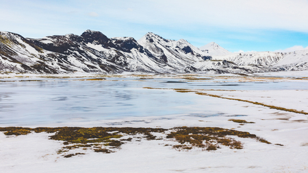 Winter landscape in Iceland. A frozen lake and snow covered mountains on background in a typical Icelandic view. Travel and wild nature conceptsの写真素材