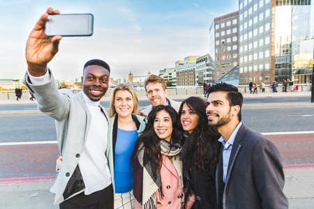 Group of business people taking a selfie in London. Mixed race group of people with Tower Bridge on background. Travel and lifestyle concepts.の写真素材