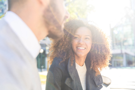 Business woman and man talking. Business people meeting on a break, chatting and laughing. Mixed race beautiful couple outdoors in the city. Business and lifestyle conceptsの写真素材