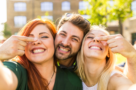 Group of friends having fun together at park and taking a selfie. Happy girls and a boy smiling and looking at camera. Lifestyle and friendship conceptsの写真素材