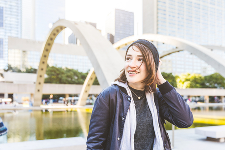Happy girl portrait in the city. Beautiful young woman, smiling and wearing hat and jacket, looking away from camera, carefree and relaxed. Lifestyle and happiness conceptsの写真素材