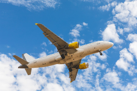 Airplane bottom view with clouds and sky on background. View of a plane landing on a sunny day. Travel, transportation and wanderlust concepts.の写真素材
