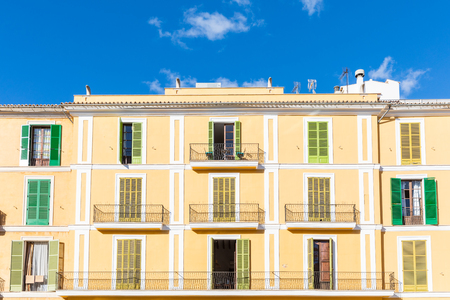 Apartment building facade with colourful shutters in Majorca. Typical mediterranean architecture and colors. Summer travel and vacations conceptsの写真素材