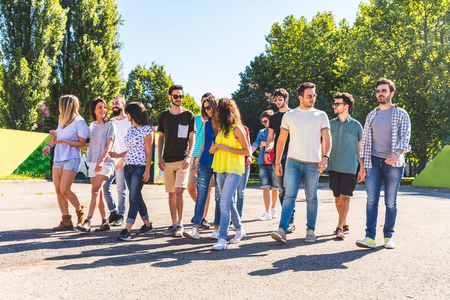 Large group of friends walking together at park. Multi ethnic group of people talking and walking on a sunny day. Friendship and lifestyle conceptsの写真素材