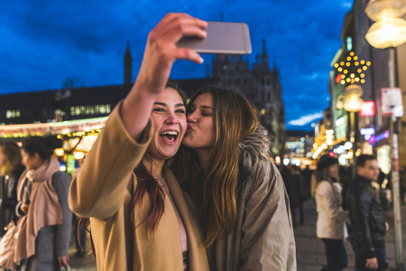 Happy girls taking a selfie together at Christmas market in Munich. Two teenage best friends having...