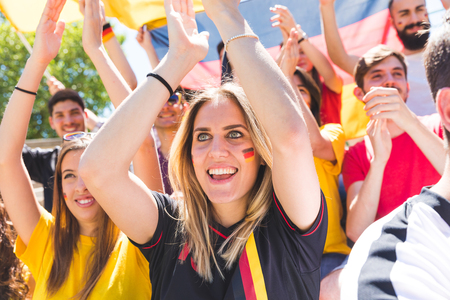 German supporters celebrating at stadium for football match. Group of fans and friends watching a match and cheering team Germany for international competition. Sport and lifestyle concepts.の写真素材