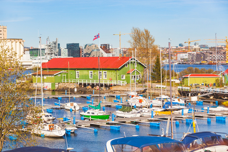 Boats in the harbour with warehouse and Oslo city on background. Typical colourful buildings in nordic countries on the seafront with boats in the port. Travel and summer conceptsの写真素材