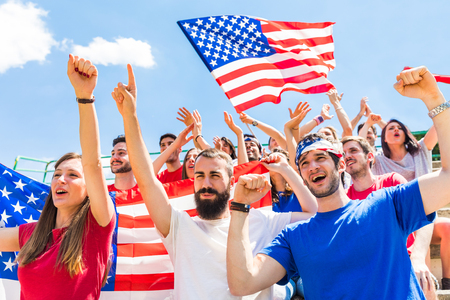 American fans cheering at stadium with USA flags. Group of supporters watching a match and cheering team USA. Sport and lifestyle concepts.の写真素材