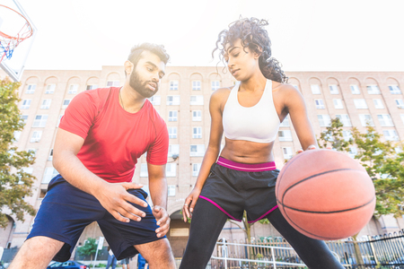 Woman vs man playing basketball in Toronto. Instructor and junior athlete on the court during a training session. Sport and urban concepts.の写真素材