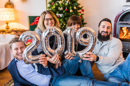 Happy people, friends celebrating new year 2019. Young men and women smiling, laughing and holding 2019 balloon sign on new year's eve celebrations. Lifestyle and holidaysの写真素材
