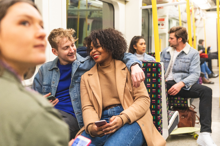 Multiracial couple travelling by tube together - White man and black woman together in subway train...