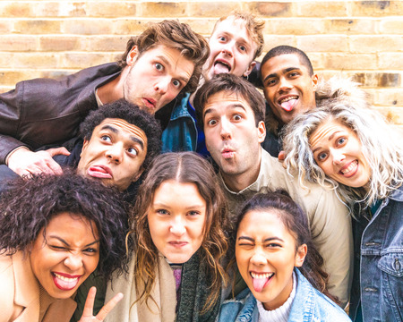 Multiracial friends taking selfie and making funny faces - Group of millennials men and women...