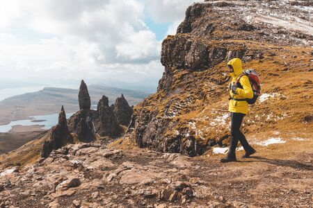 Man hiking in Scotland, Isle of Skye at the Old Man of Storr - Hiker looking at the beautiful panorama with the famous rocks of the Isle of Skye on a autumn or winter day - Filter applied, travel and adventure conceptsの写真素材
