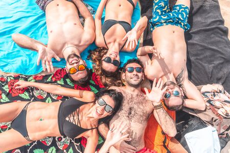 Happy friends relaxing on the beach in Barcelona - Multiracial group of best friends enjoying summer time together cheering and waving at camera - Happiness and friendship during a travel in Spainの写真素材