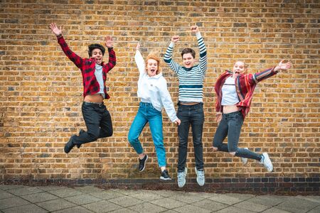 Happy teen friends jumping in front of a wall in London - Multiracial group of teenagers best friends enjoying time together and having fun - Lifestyle and friendship in Londonの写真素材