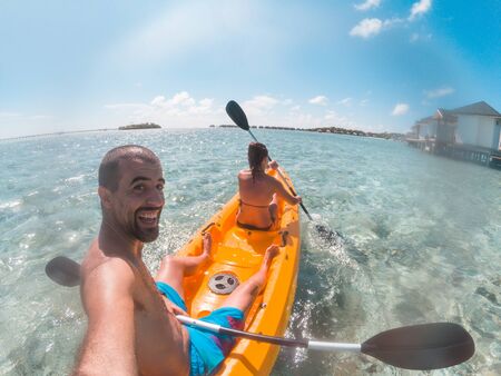 Couple on a kayak at Maldives seaside resort - Young happy couple enjoying summer vacation and having fun in a canoe on the water - Summer and sport conceptsの写真素材