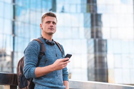Pensive man using phone portrait with modern buildings on background - Thoughtful man alone in the...
