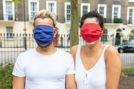 Happy couple taking a selfie with face mask on - Young man and woman taking a self portrait together and greeting the camera with hand gestures - lifestyle and happiness during coronavirurs pandemicの写真素材