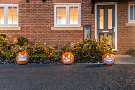 Halloween pumpkins wearing a face mask against coronavirus in front of a home entrance - Halloween theme during covid 19 pandemic - Culture and lifestyleの写真素材