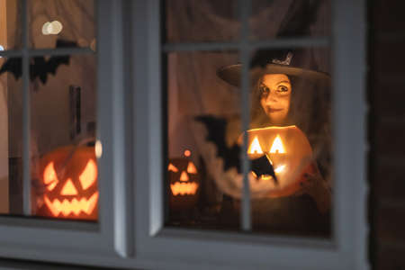 Woman witch carrying a pumpkin for Halloween night - Spooky scene with halloween symbols and signs  - holidays, culture and lifestyle in UK and United Statesの写真素材