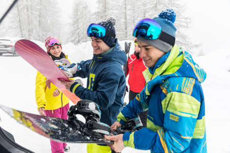 Happy friends with ski and snowboard - Winter sport scene with a group of young people wearing skiing clothes and smiling - Sport and lifestyle conceptsの写真素材