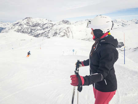 Happy woman with ski on top of mountain slopes - Beautiful young woman enjoying ski holidays and having fun on the snow on a beautiful sunny winter day in Livigno - Sport and travel conceptsの写真素材