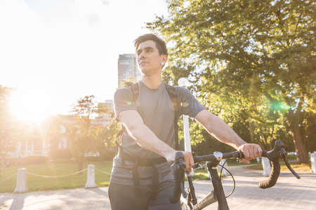 Man walking carrying his bike in Chicago - Young caucasian man smiling on his commute in the city -...
