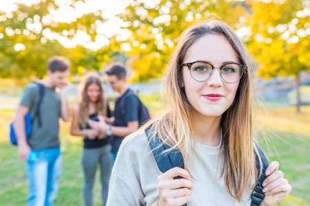 Teen student with friends at park - Smiling and confident girl looking at camera on back to school day - Lifestyle and friendship conceptsの写真素材