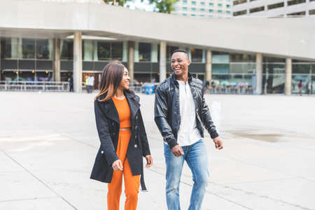 Happy black couple having fun in Toronto - Man and woman walking and laughing in the city during the day - Lifestyle and friendship or love conceptsの写真素材