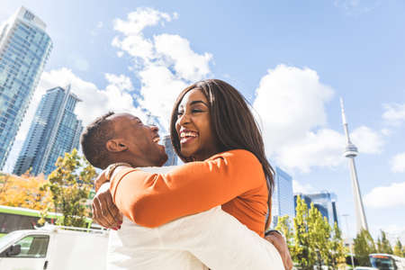 Happy black couple having fun in Toronto - Man and woman embracing and laughing in the city during the day - Lifestyle and friendship or love conceptsの写真素材