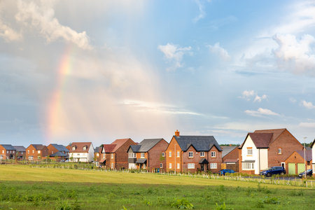 Houses in a new development estate in England with green grass and rainbow in the sky - View of typical English homes and weather - Architecture and building conceptsの写真素材
