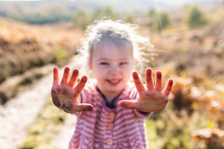 Smiling happy girl showing dirty hands after playing on the ground - Cute girl enjoying a day out...