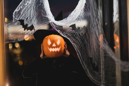 Woman witch carrying a pumpkin for Halloween night - Spooky scene with halloween symbols and signs  - holidays, culture and lifestyle in UK and United Statesの写真素材