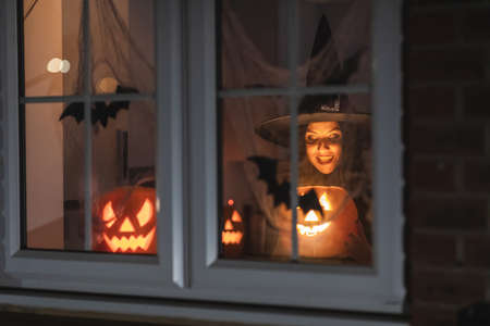 Woman witch carrying a pumpkin for Halloween night - Spooky scene with halloween symbols and signs  - holidays, culture and lifestyle in UK and United Statesの写真素材